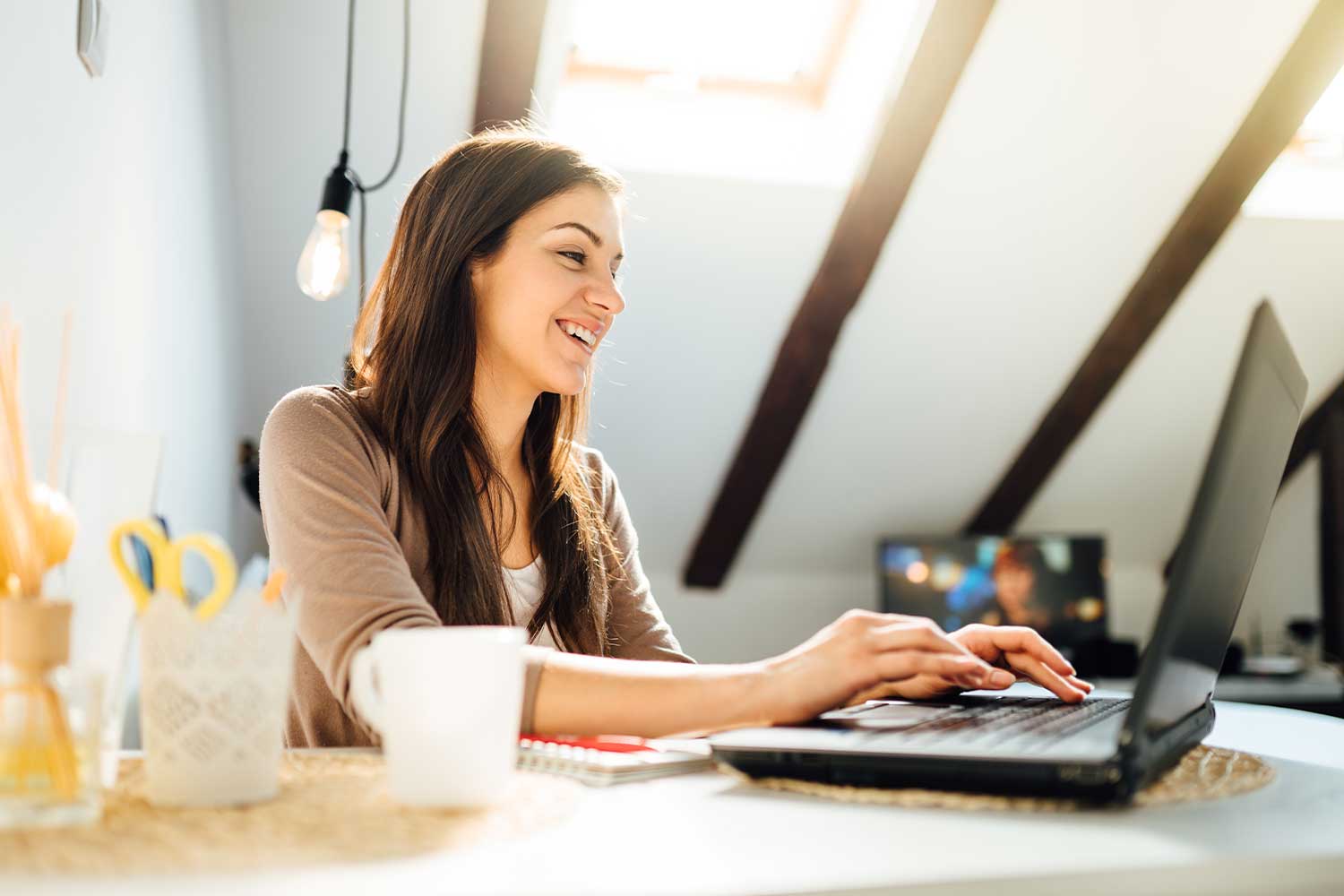 A woman with long dark hair smiling at her laptop during a virtual coaching and consulting session